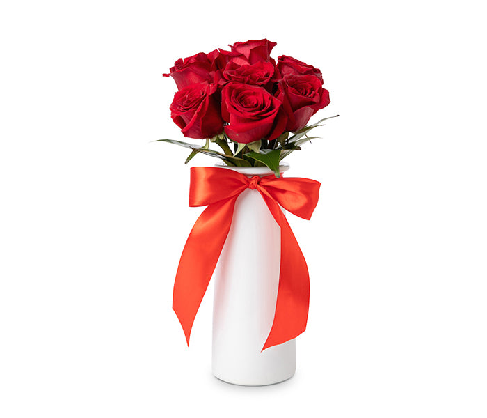 Small slender white vase with 7 red roses.