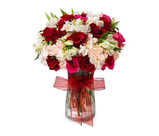 Clear vase with red and pink roses, hydrangeas and alstromeria.