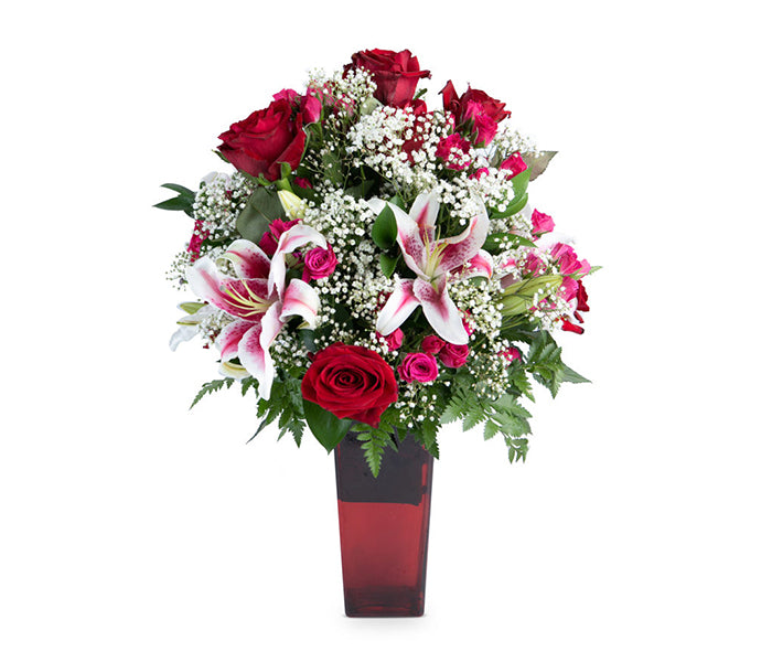 Slender vase with red roses, stargazer lilies, spray roses and baby’s breath.